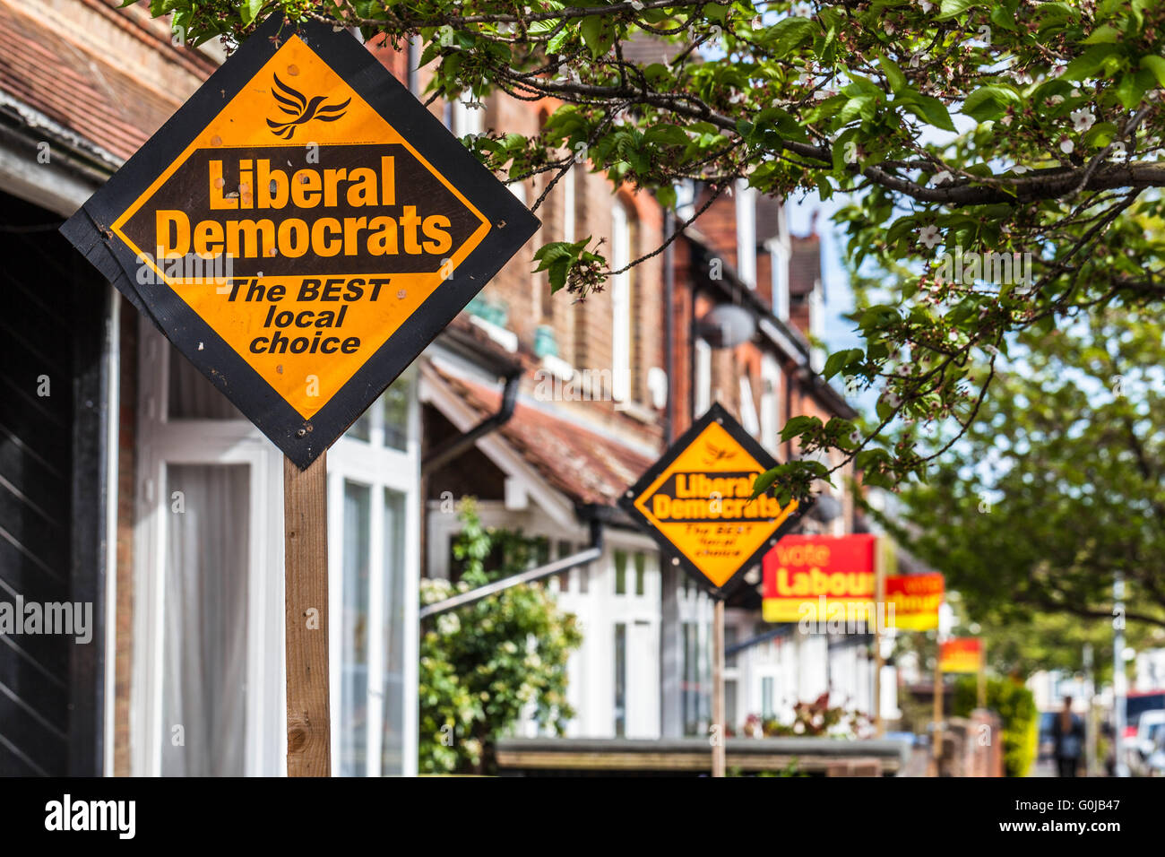 Fila di case a schiera la visualizzazione di partiti politici pole segni in periodo elettorale, Watford, Hertfordshire, Inghilterra, Regno Unito. Foto Stock
