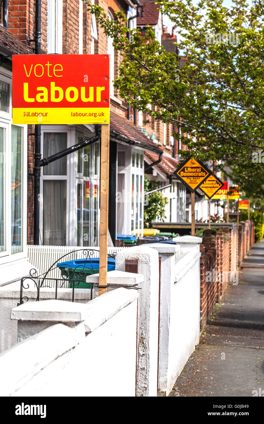 Fila di case a schiera la visualizzazione di partiti politici pole segni in periodo elettorale, Watford, Hertfordshire, Inghilterra, Regno Unito Foto Stock