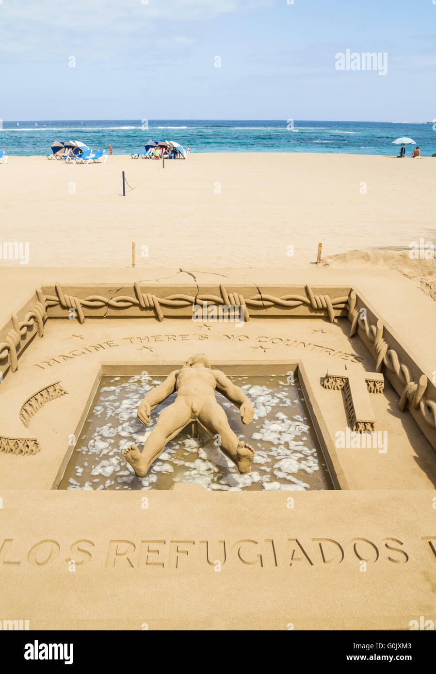 Crisi di rifugiati la scultura di sabbia, Las Palmas di Gran Canaria Isole Canarie Spagna, 1 maggio 2016. Scultore di sabbia/artista Etual Ojeda crea un stuning la scultura di sabbia sulla spiaggia cittadina e rende omaggio ai rifugiati che hanno perso la vita sul mare infido attraversamenti. L intricato lavoro mostra una persona galleggiante sull'acqua circondata da filo spinato con le parole 'immaginare non ci sono paesi" sopra la sua testa. Sotto i suoi piedi le parole "Homenaje a los refugiados del mundo". (Omaggio a dei rifugiati del mondo). Credito: Alan Dawson News/Alamy Live News Foto Stock