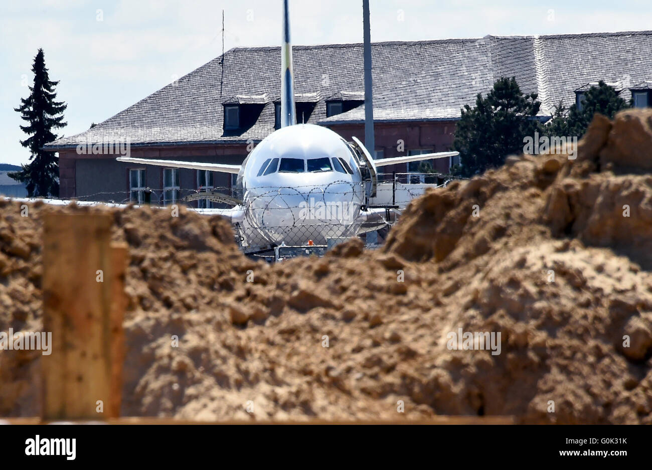 Un airplan parcheggio dietro un sito in costruzione presso il Terminal D all'aeroporto di Schoenefeld, Germania, 2 maggio 2016. Direttamente accanto al terminale del vecchio campo d'aviazione, le posizioni di parcheggio per le macchine di compagnie aeree a basso costo sono costruiti, che dopo l'apertura di Willy Brandt Aeroporto BER non avrà abbastanza spazio più. Foto: BERND SETTNIK/dpa Foto Stock