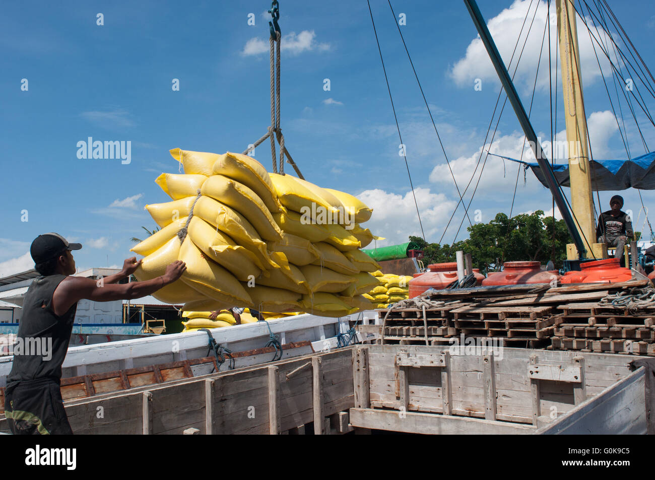 Lavoratori caricati sacchi di cemento nello scafo di una imbarcazione a Paotere Porto di Makassar, Indonesia. Foto Stock