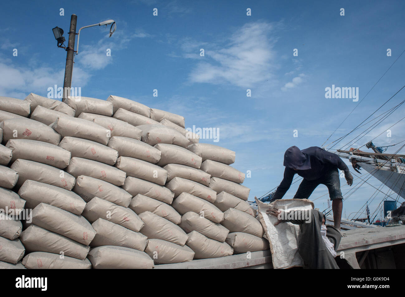 Gli uomini si muovono un sacco di cemento a Paotere Porto di Makassar, Indonesia. Foto Stock