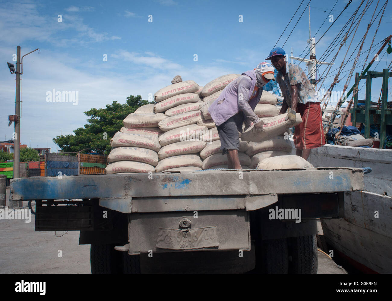 Lavoratori caricati sacchi di cemento per lo scafo di una imbarcazione a Paotere Porto di Makassar, Indonesia. Foto Stock