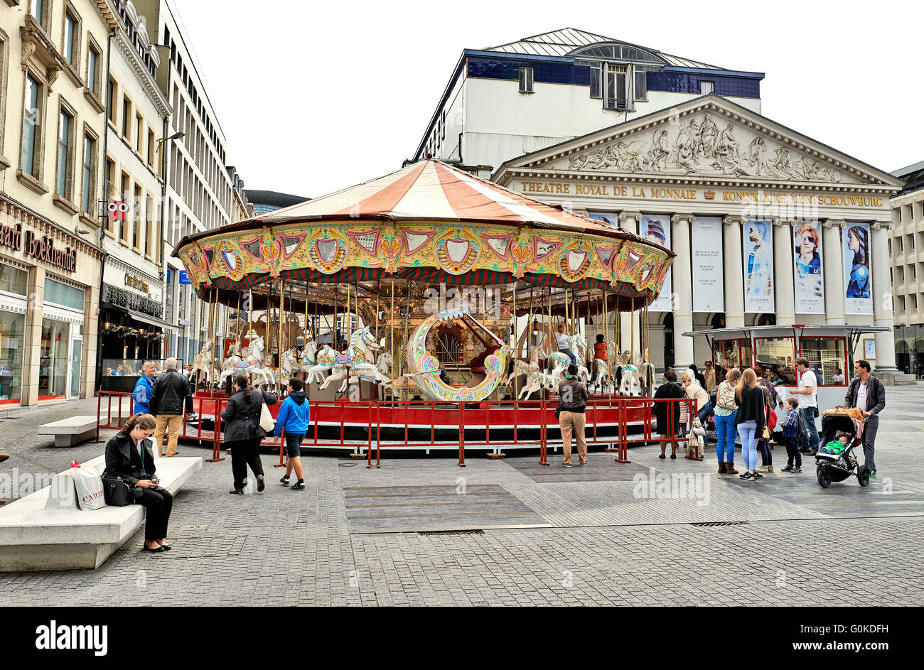 Alcune persone godono di una splendida giornata di settembre intorno a una giostra installato nella parte anteriore del Royal Theatre la Monnaie di Bruxelles. Foto Stock