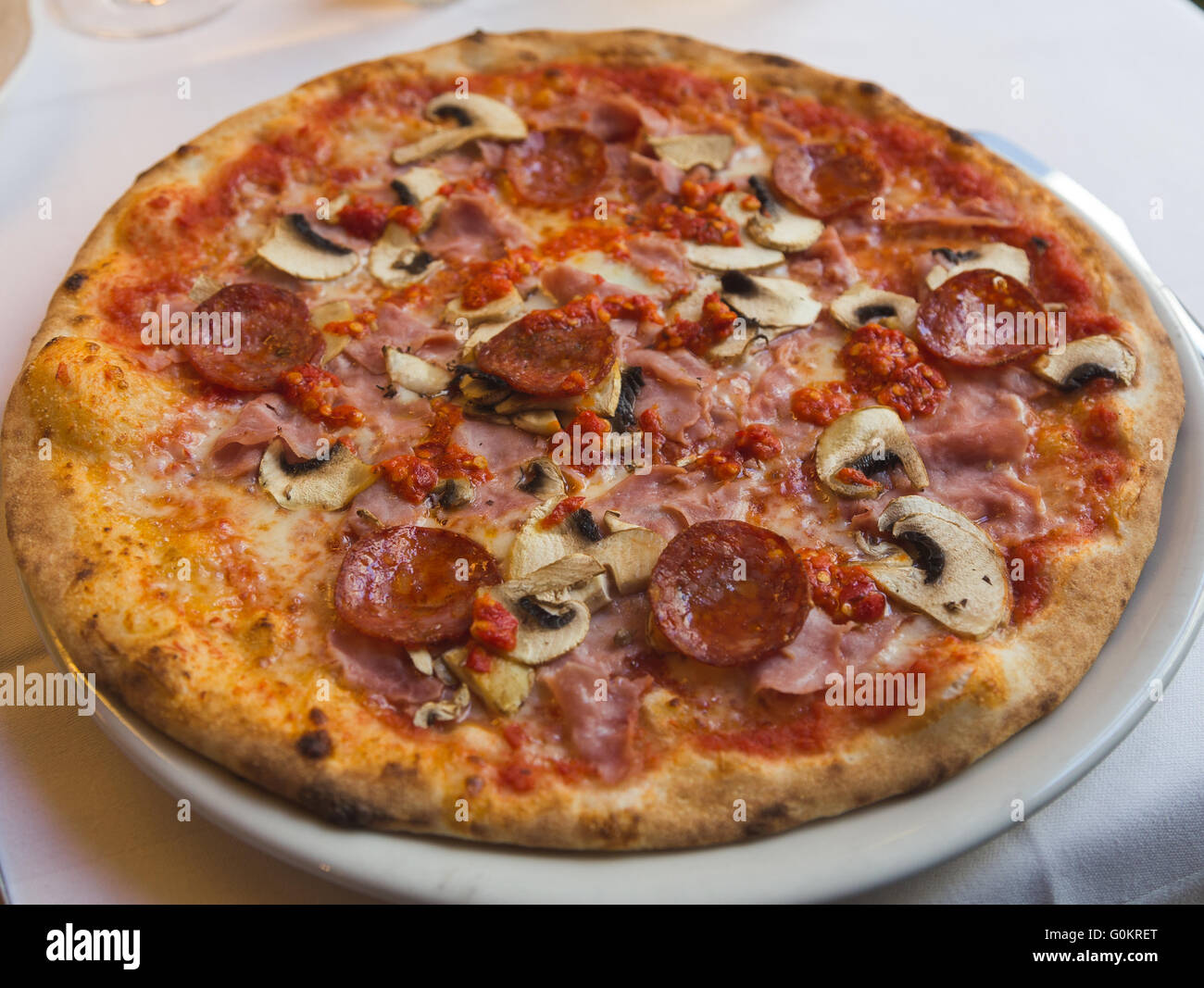 Elevato angolo di un salame, prosciutto, funghi, peperoncino e Tomatoe Pizza italiana Foto Stock