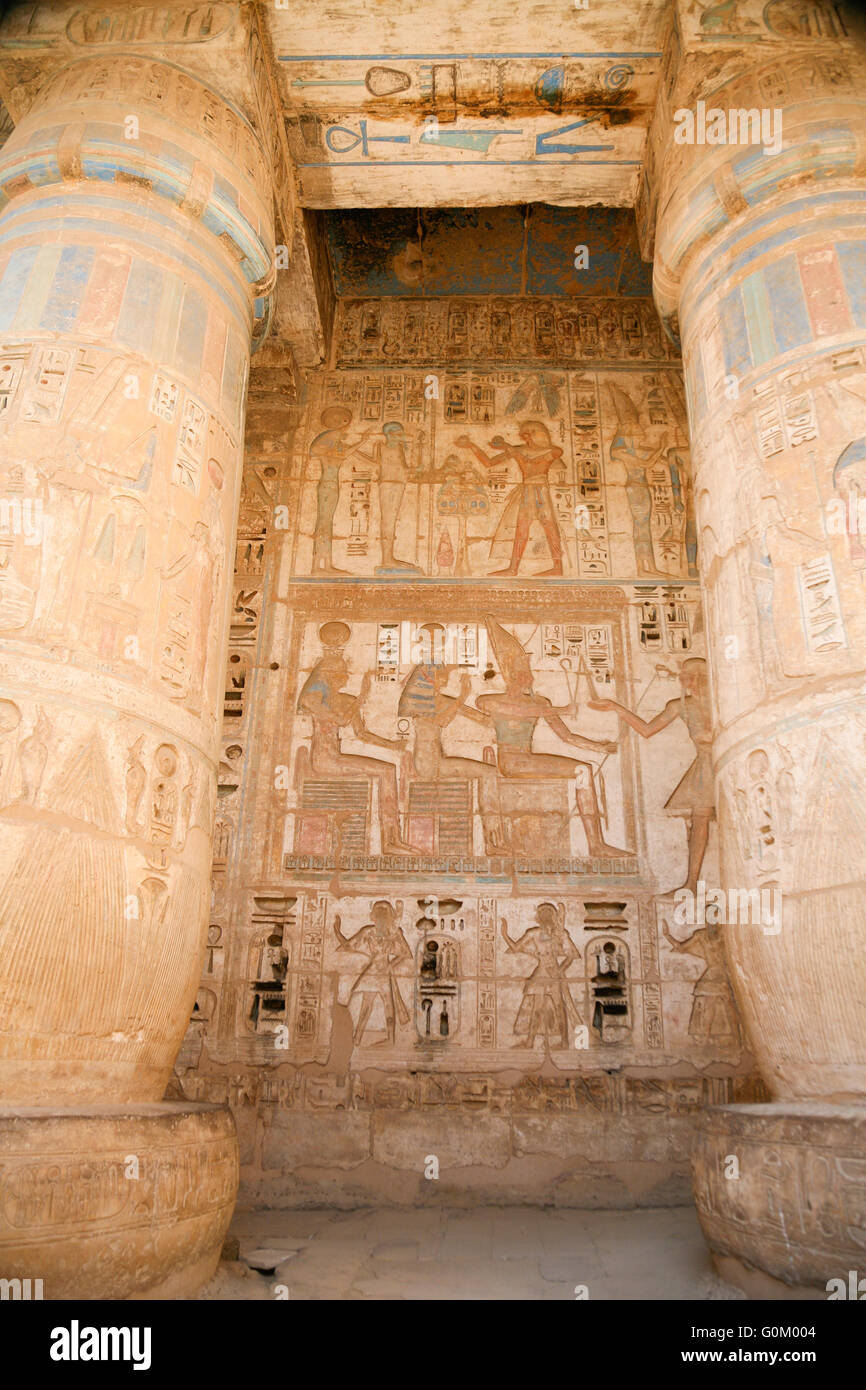 Dipinti egiziani, carving figure e geroglifici in colonne e una parete di pietra miliare tempio di Ramses o Ramesse III a Medinet Foto Stock