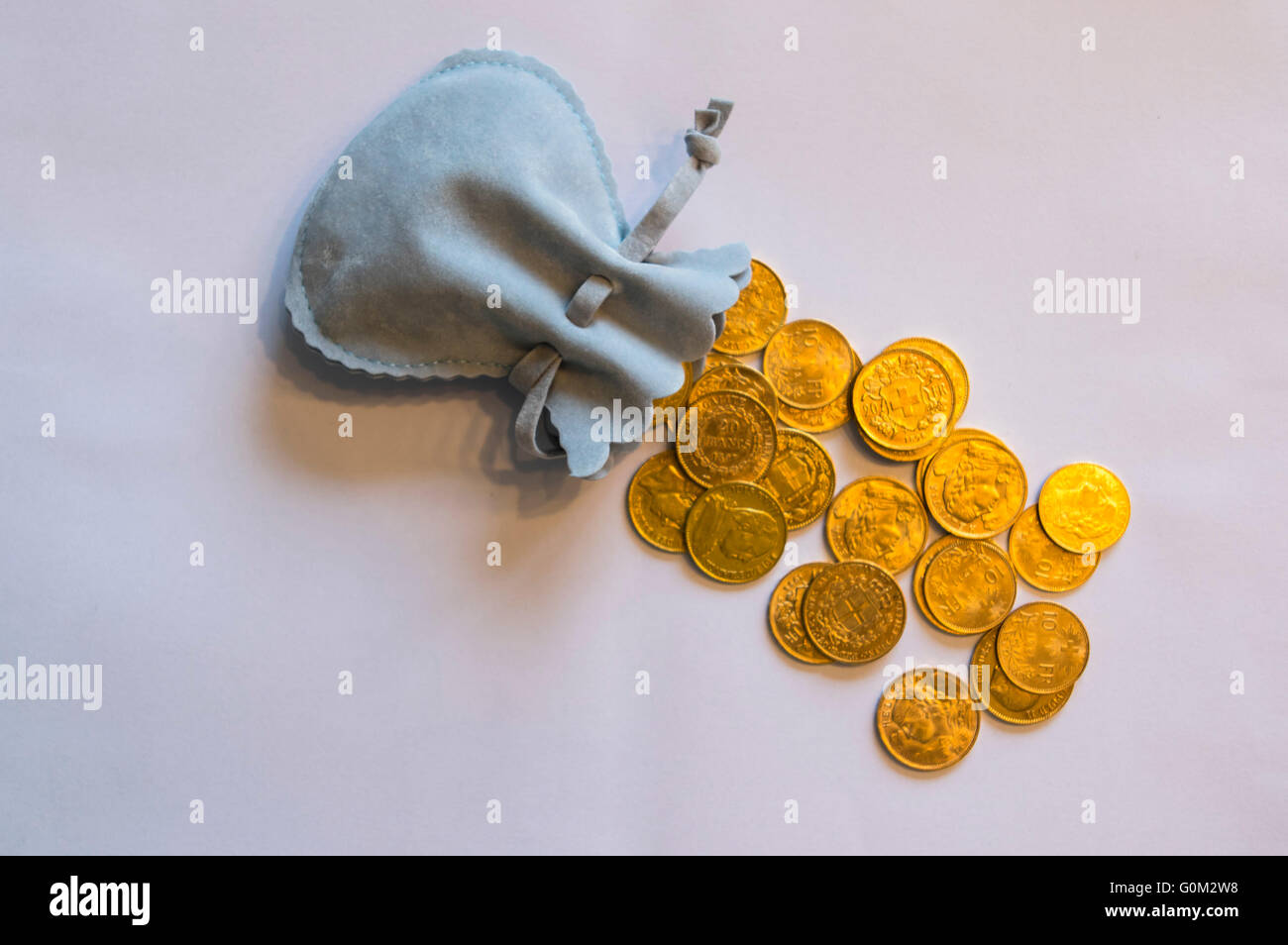 Molte monete d oro versata al di fuori di un piccolo portamonete. La maggior parte sono del XIX e XX secolo 20 franchi svizzeri monete d'oro. Foto Stock