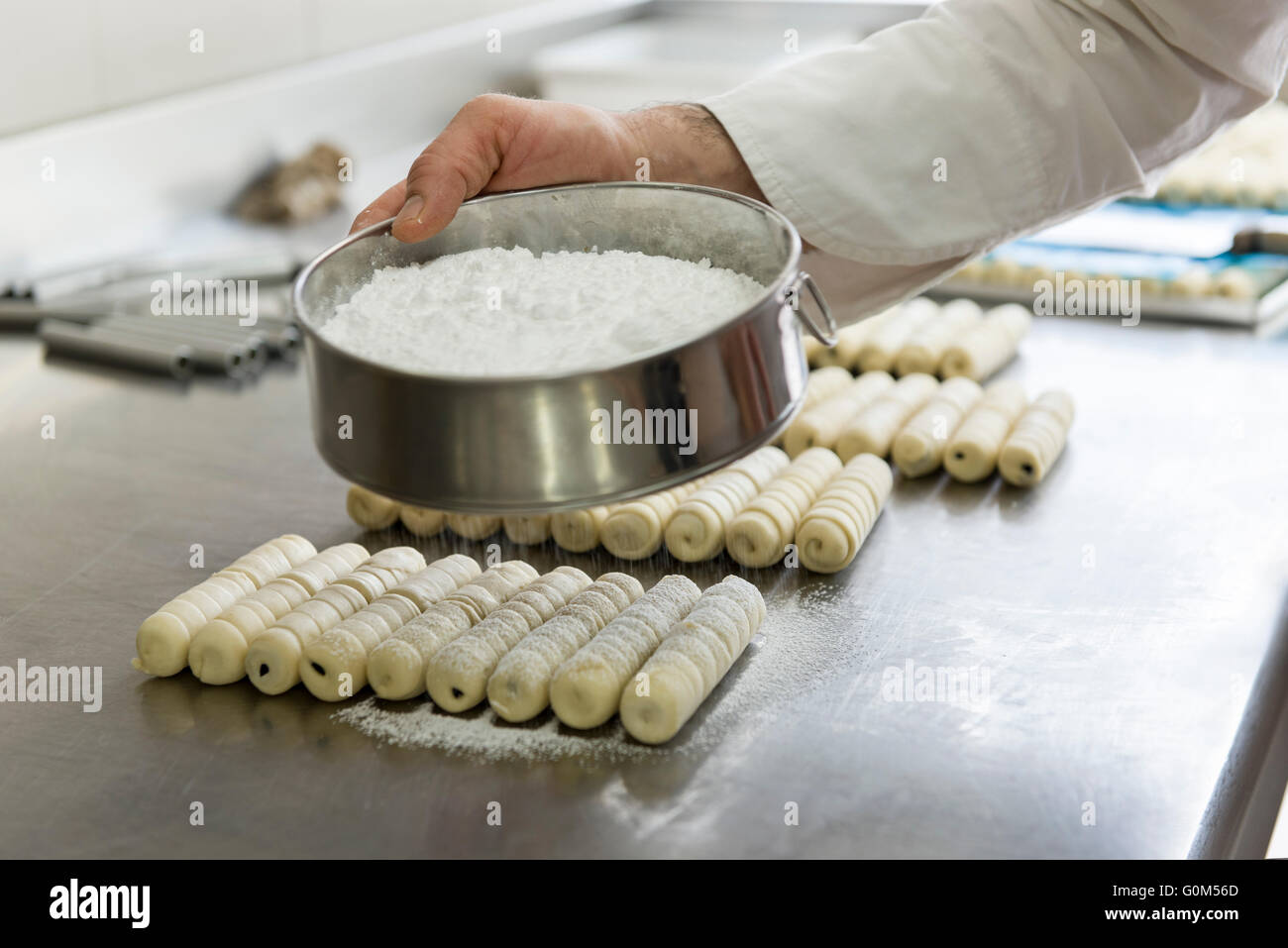 Pastry chef che copre la pasta con zucchero a velo Foto Stock