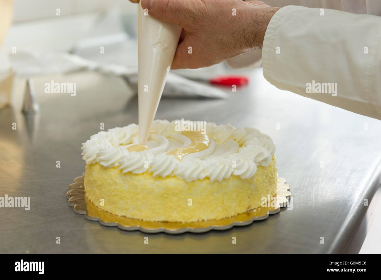 Pastry chef guarnire una torta con crema Foto Stock
