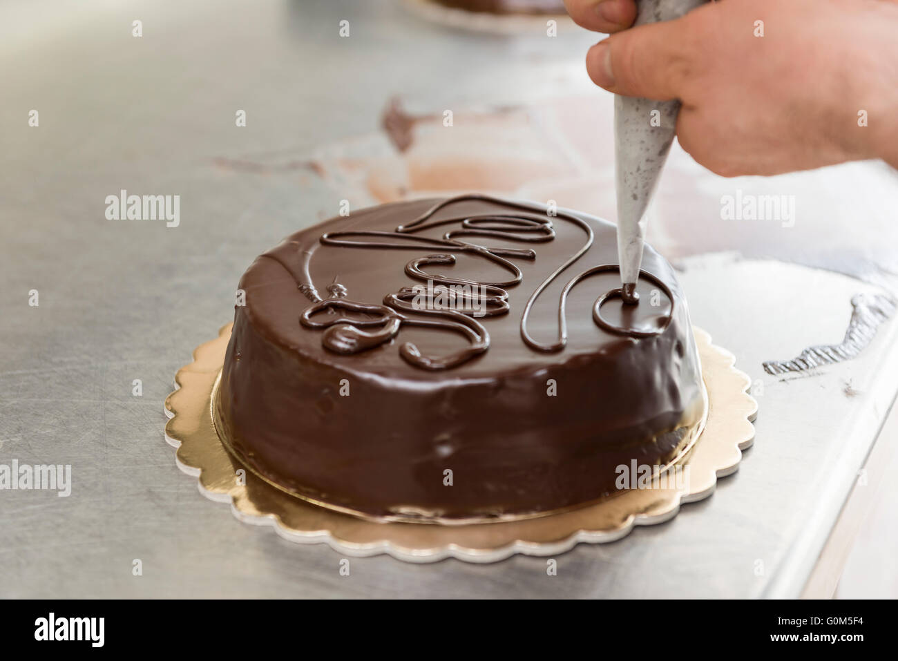 Pastry chef guarnire una torta al cioccolato fuso Foto Stock