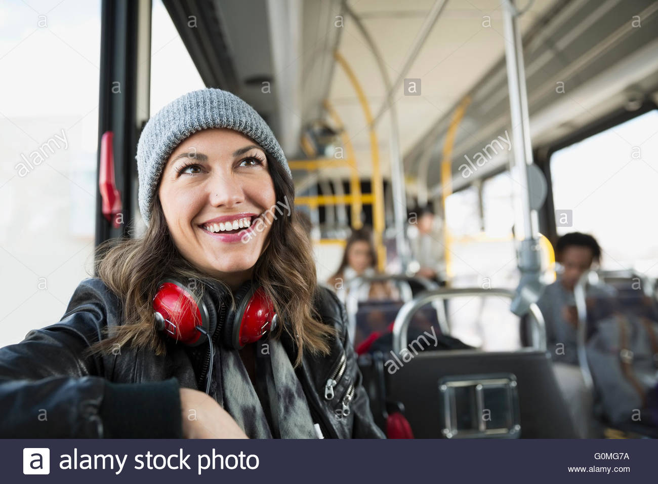Donna sorridente con cuffie bus di equitazione Foto Stock