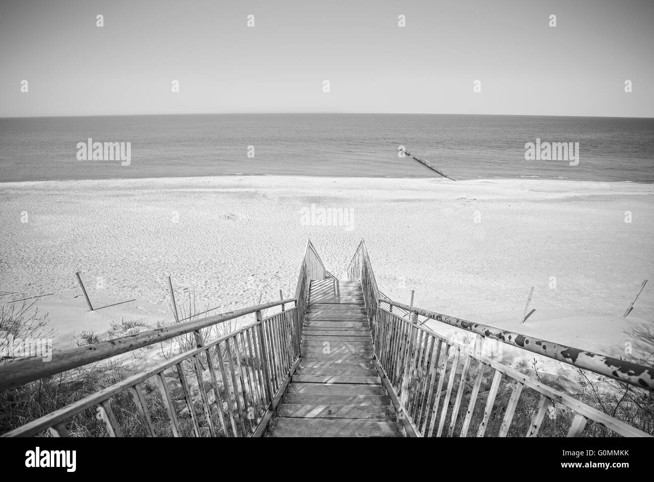 Foto in bianco e nero di scale di legno sulla spiaggia. Foto Stock