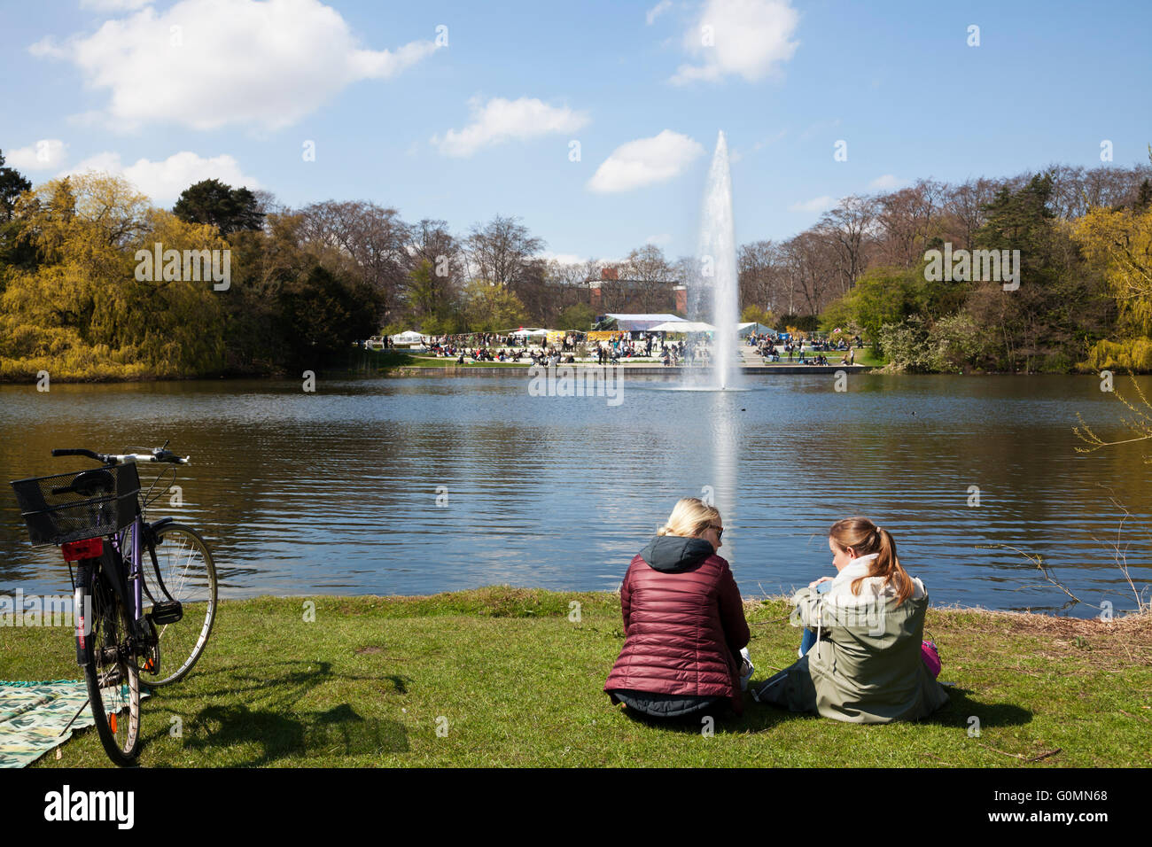 Ragazza e donne godono la giornata di sole a Faelledparken, il comune di Copenaghen, in occasione delle celebrazioni del Labor Day che si svolgono intorno a loro. Ambiente, accogliente, hygge Foto Stock