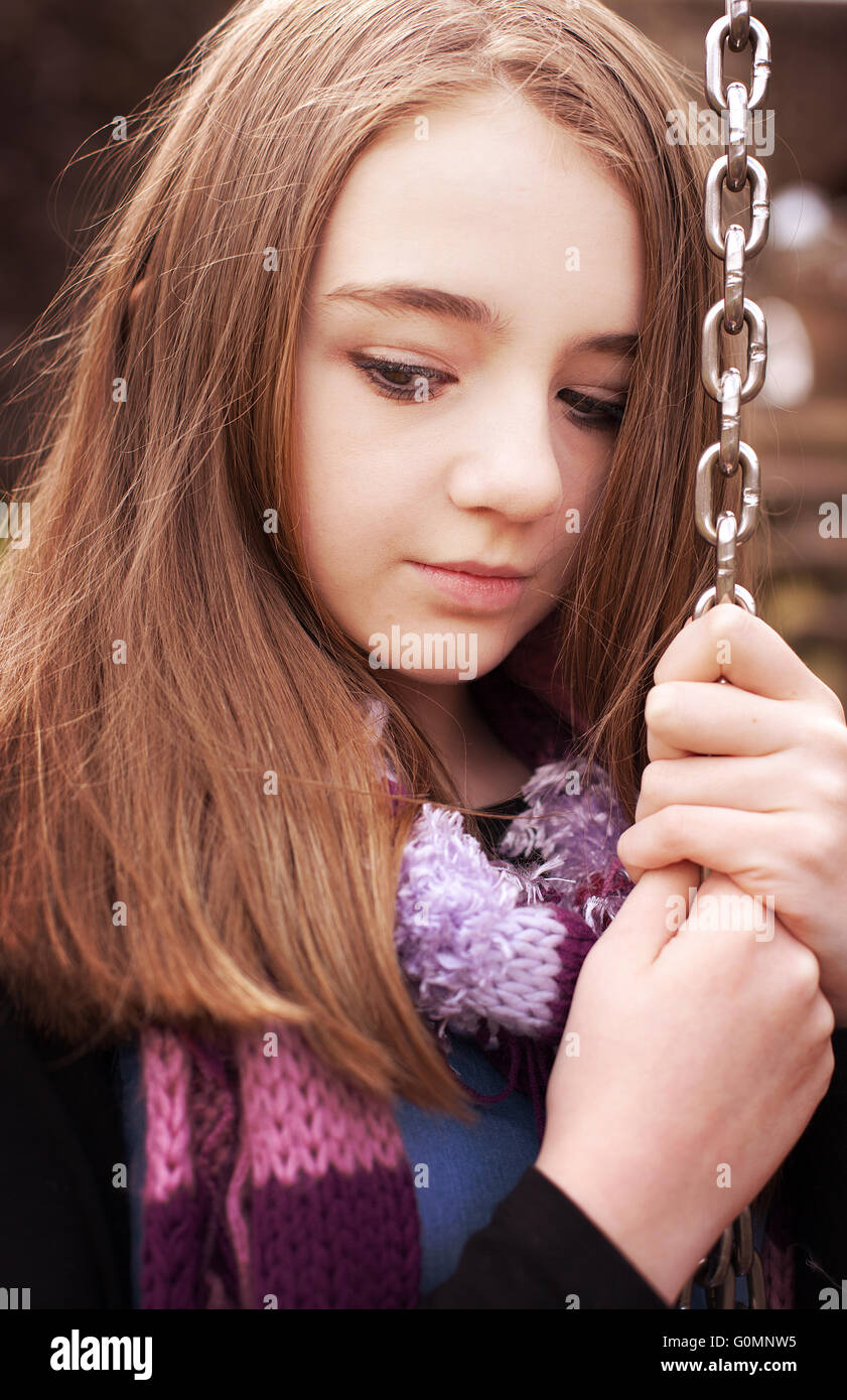 Bella ragazza adolescente tenendo premuto su di una catena da uno swing Foto Stock