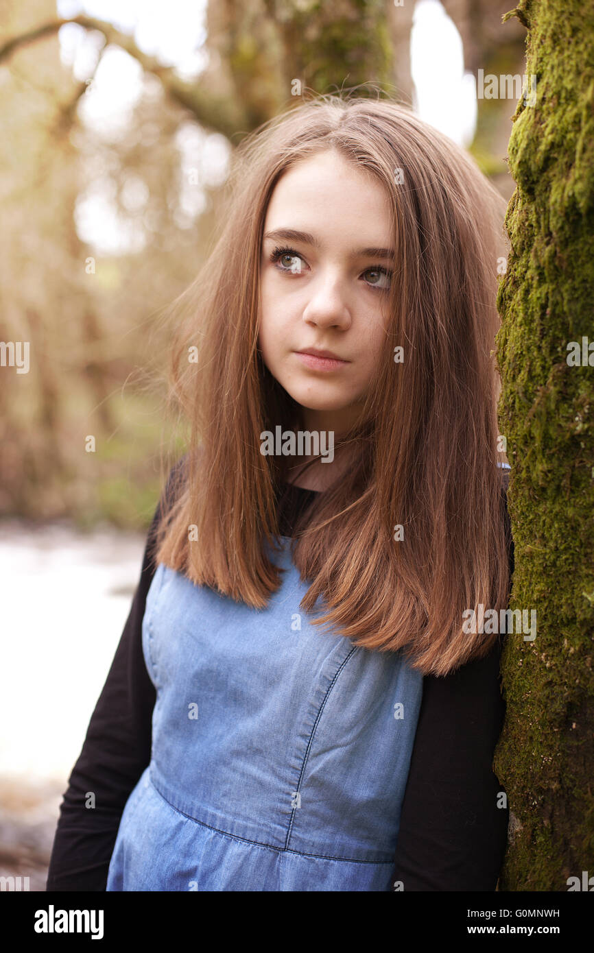 Bella ragazza adolescente guardando verso l'alto mentre appoggiato su di un albero di muschio Foto Stock