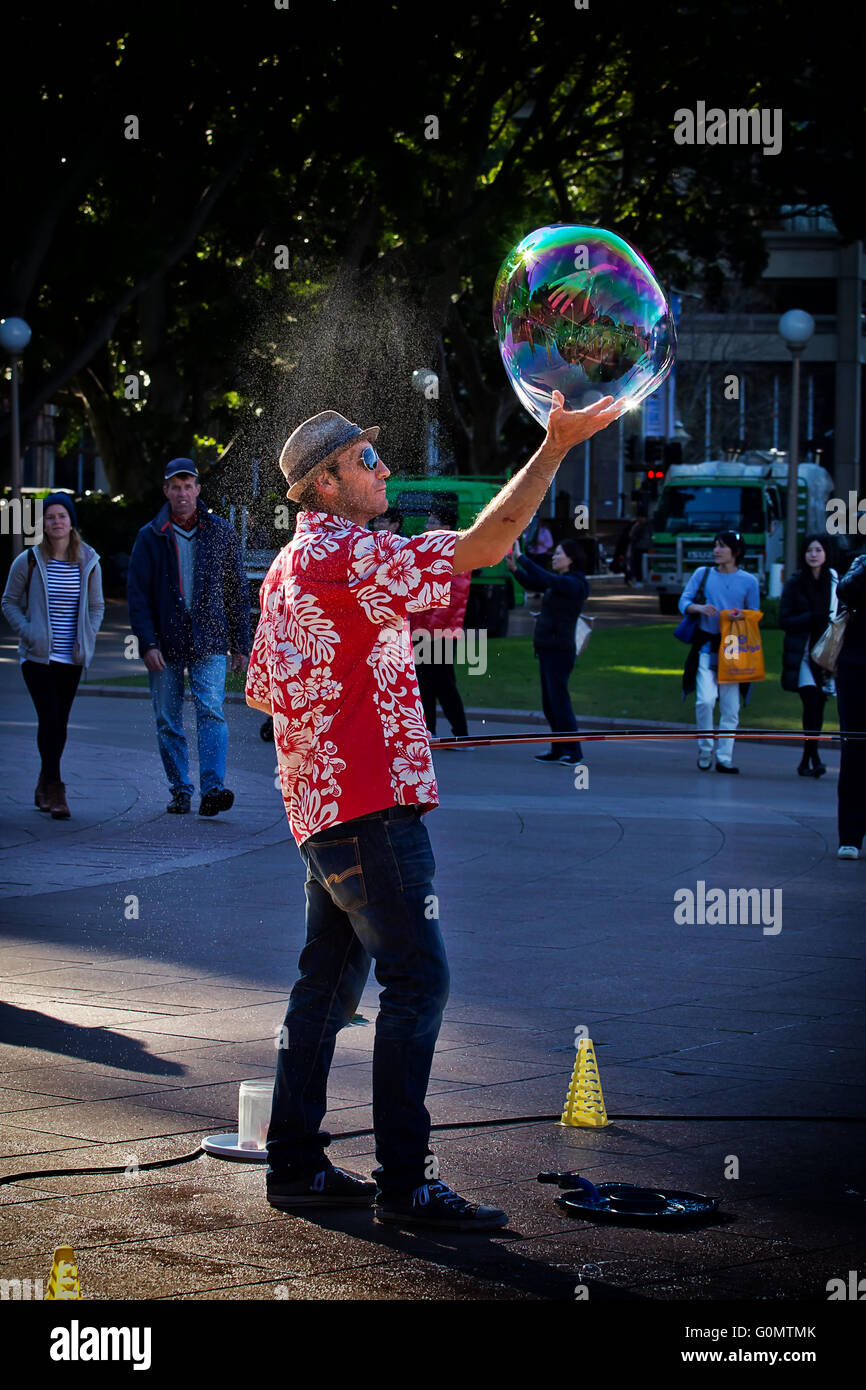Un esecutore di strada gira una bolla di sapone nel palmo della mano Foto Stock