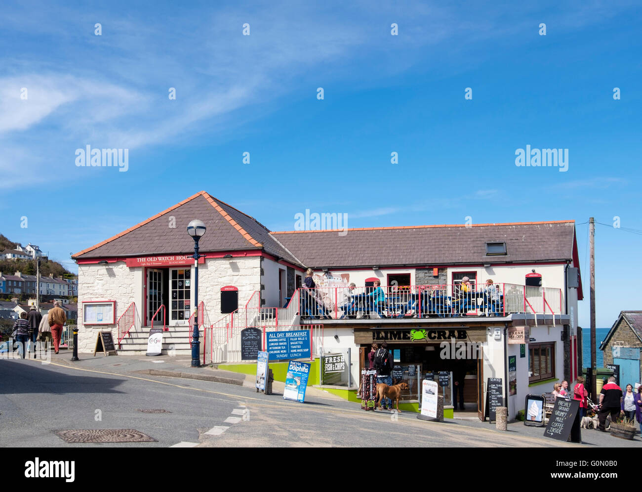 Il vecchio orologio Casa cafe e ristorante con pesce e Chip shop sotto nel villaggio di pescatori popolare con i turisti. Nuova banchina Wales UK Gran Bretagna Foto Stock