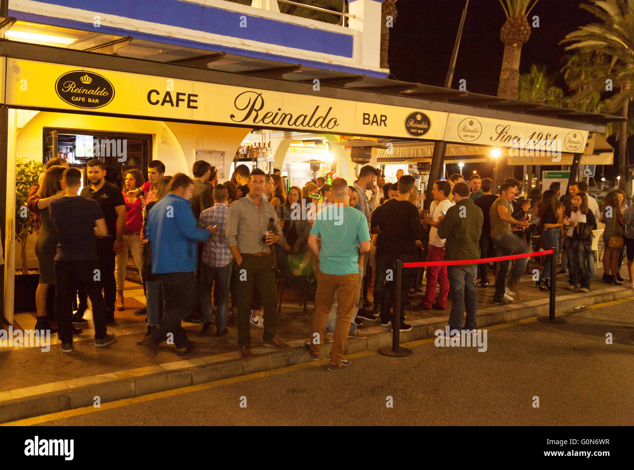 Una folla di persone in un bar di notte, Estepona marina, Costa del Sol Spagna Europa Foto Stock
