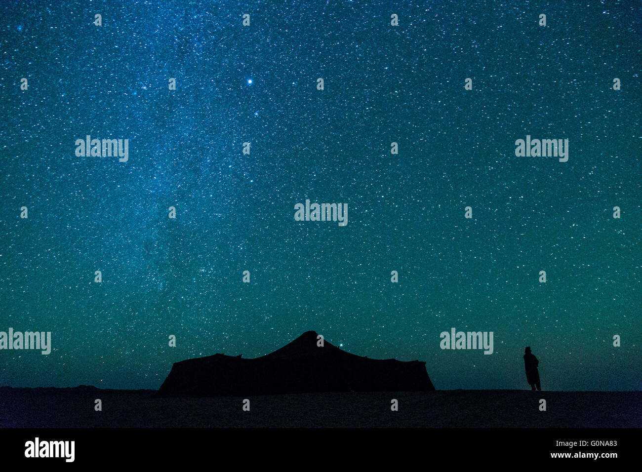 Una silhouette sotto la via lattea e un cielo stellato di fronte un haima a Merzouga Foto Stock