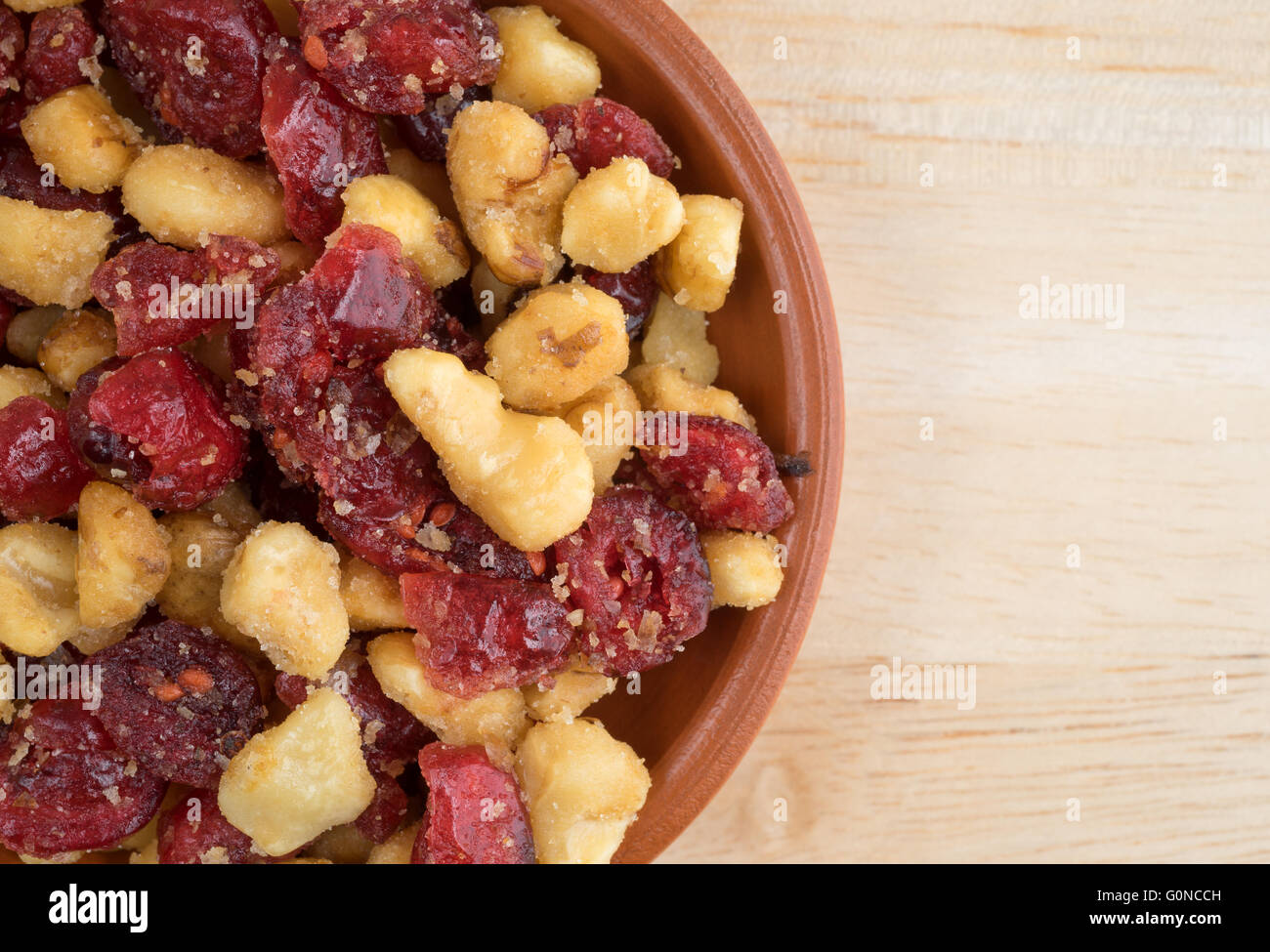 Top vista ravvicinata di una piccola ciotola riempita con mirtilli rossi e noci su una tavola di legno alto. Foto Stock