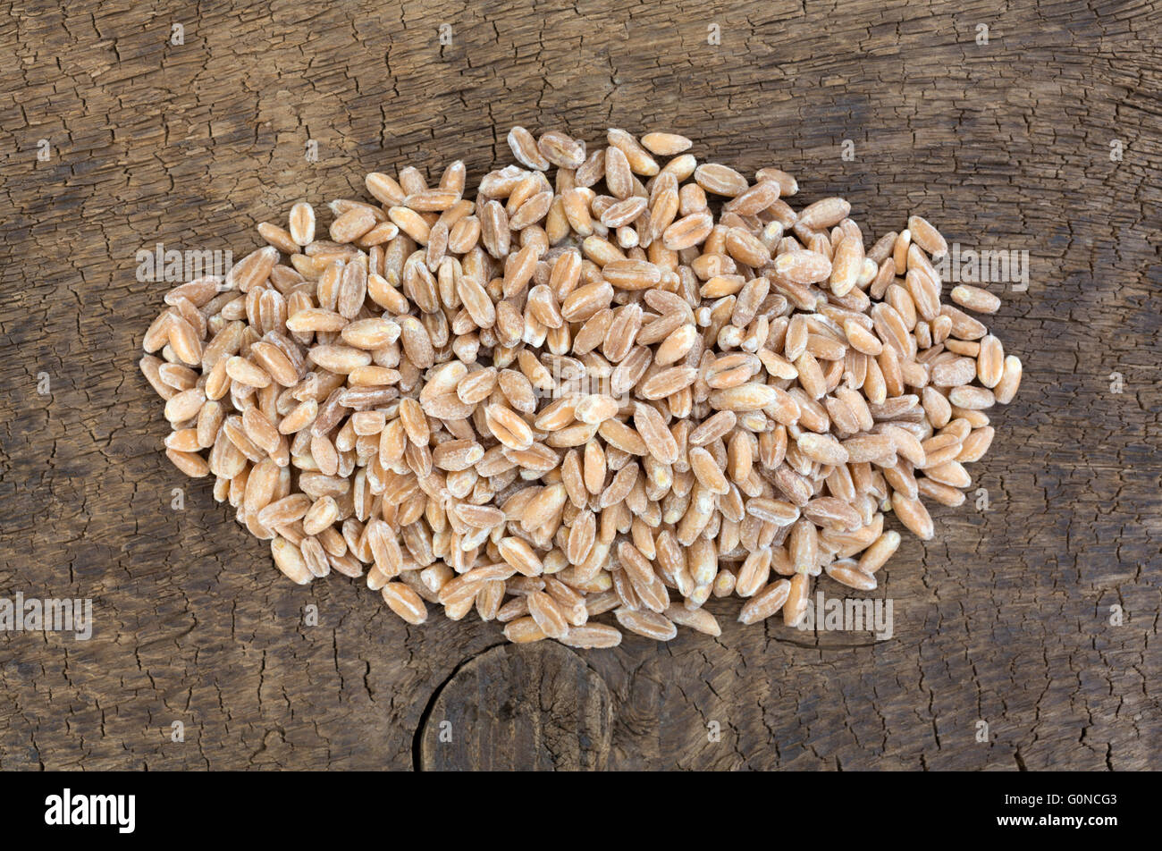 Top vista ravvicinata di una porzione di organico farrow grano su una vecchia scheda a spiovente. Foto Stock
