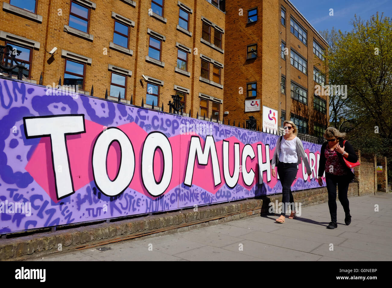 Due donne walking pass wall art 'TROPPE INFORMAZIONI' di Londra Foto Stock