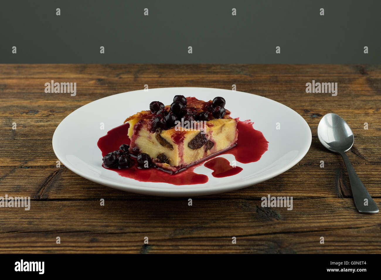 Il budino con le prugne secche, le uve secche di Corinto sulla parte superiore di una piastra bianca su una tavola di legno Foto Stock