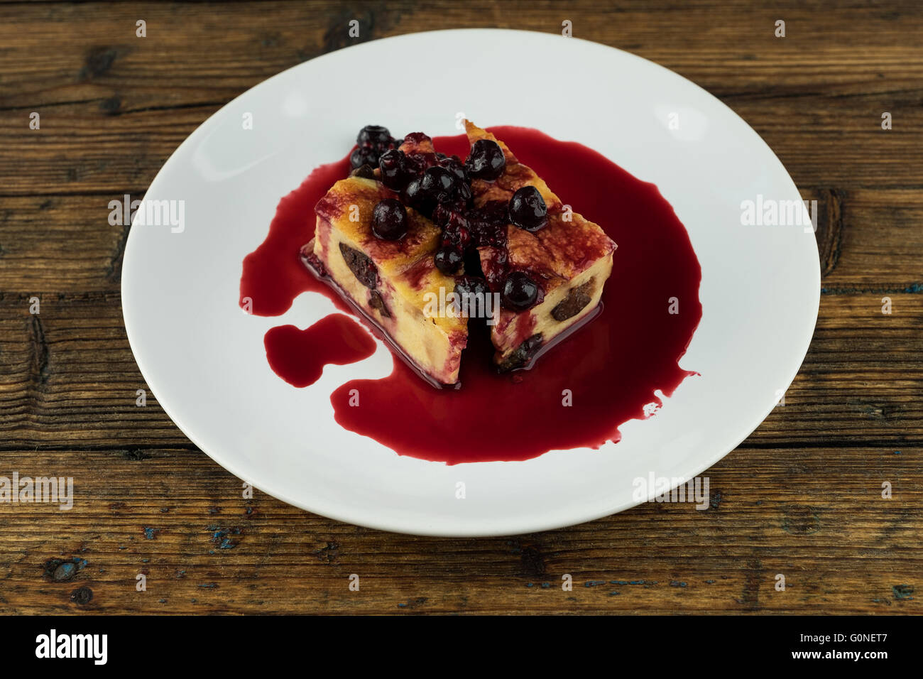 Il budino con le prugne secche, le uve secche di Corinto sulla parte superiore di una piastra bianca su una tavola di legno Foto Stock