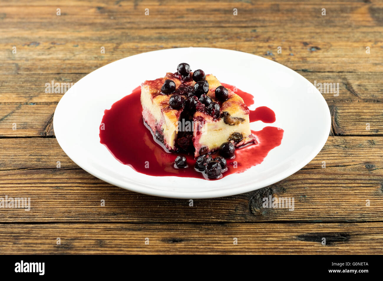 Il budino con le prugne secche, le uve secche di Corinto sulla parte superiore di una piastra bianca su una tavola di legno Foto Stock