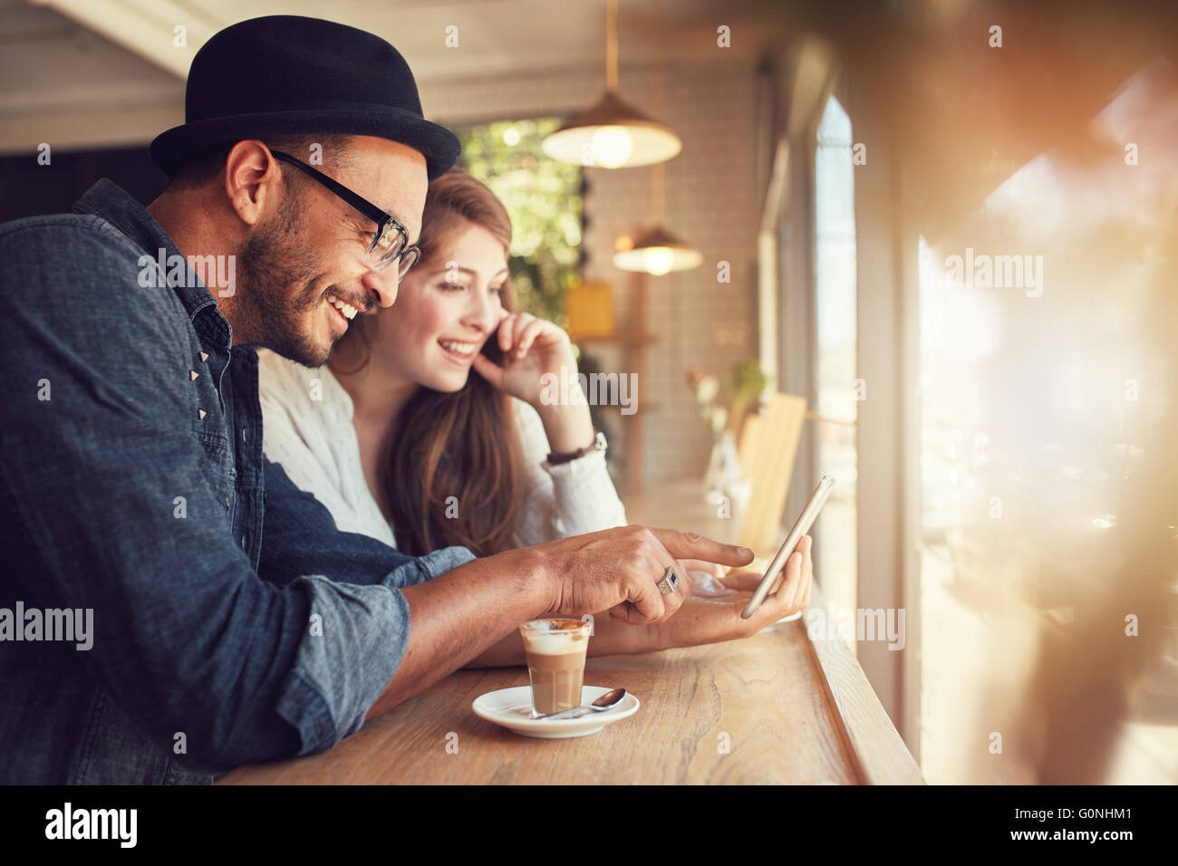 Sorridente coppia giovane in un coffee shop usando il touch screen del computer. Giovane uomo e donna in un ristorante guardando a tavoletta digitale Foto Stock