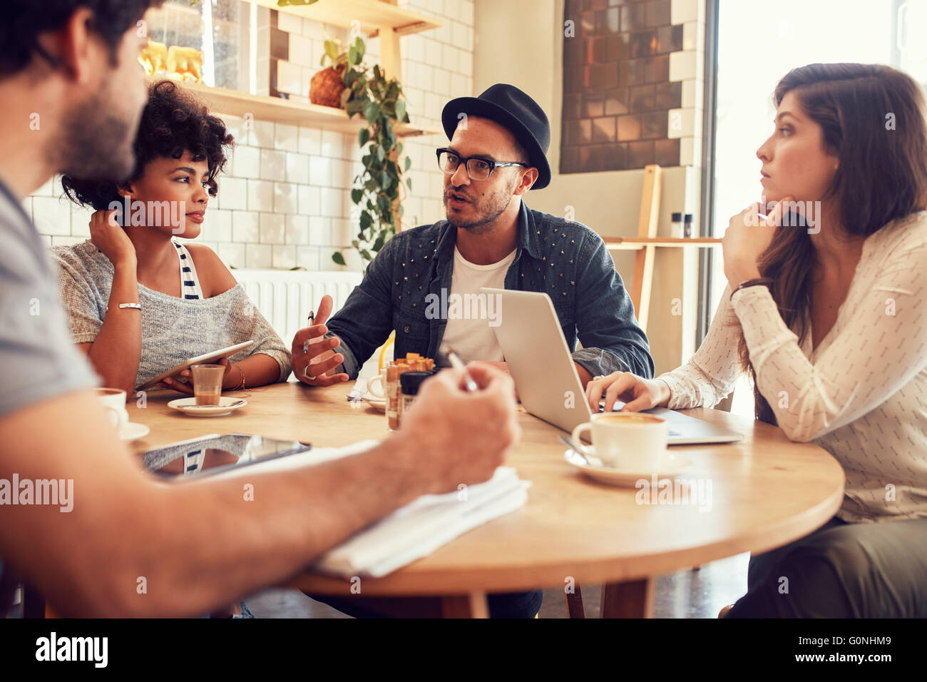 Ritratto di giovani amici seduti in un caffè e discutere. Le persone creative che si incontrano in un cafe'. Foto Stock