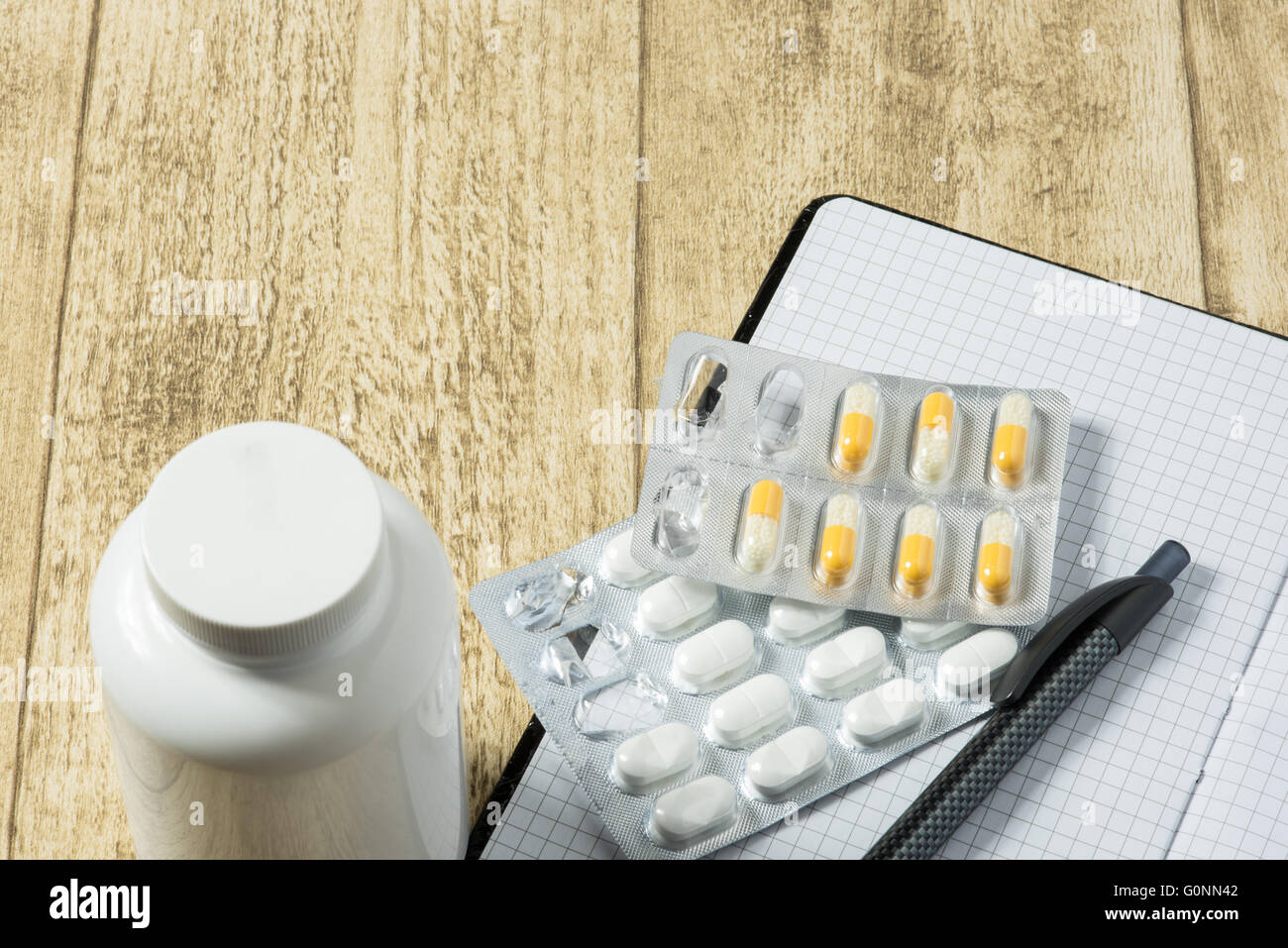 Compresse sulla scrivania in legno con notebook e penna Foto Stock