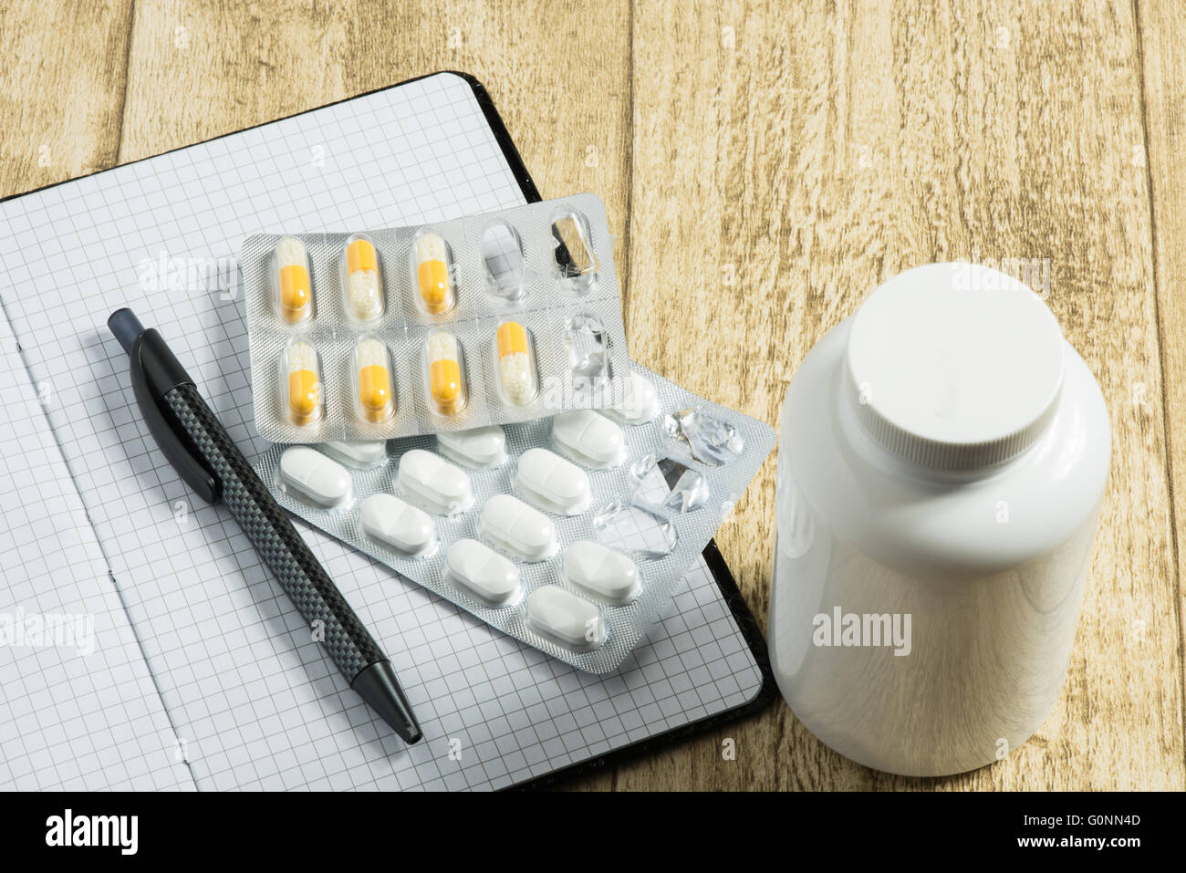 Compresse sulla scrivania in legno con notebook e penna Foto Stock