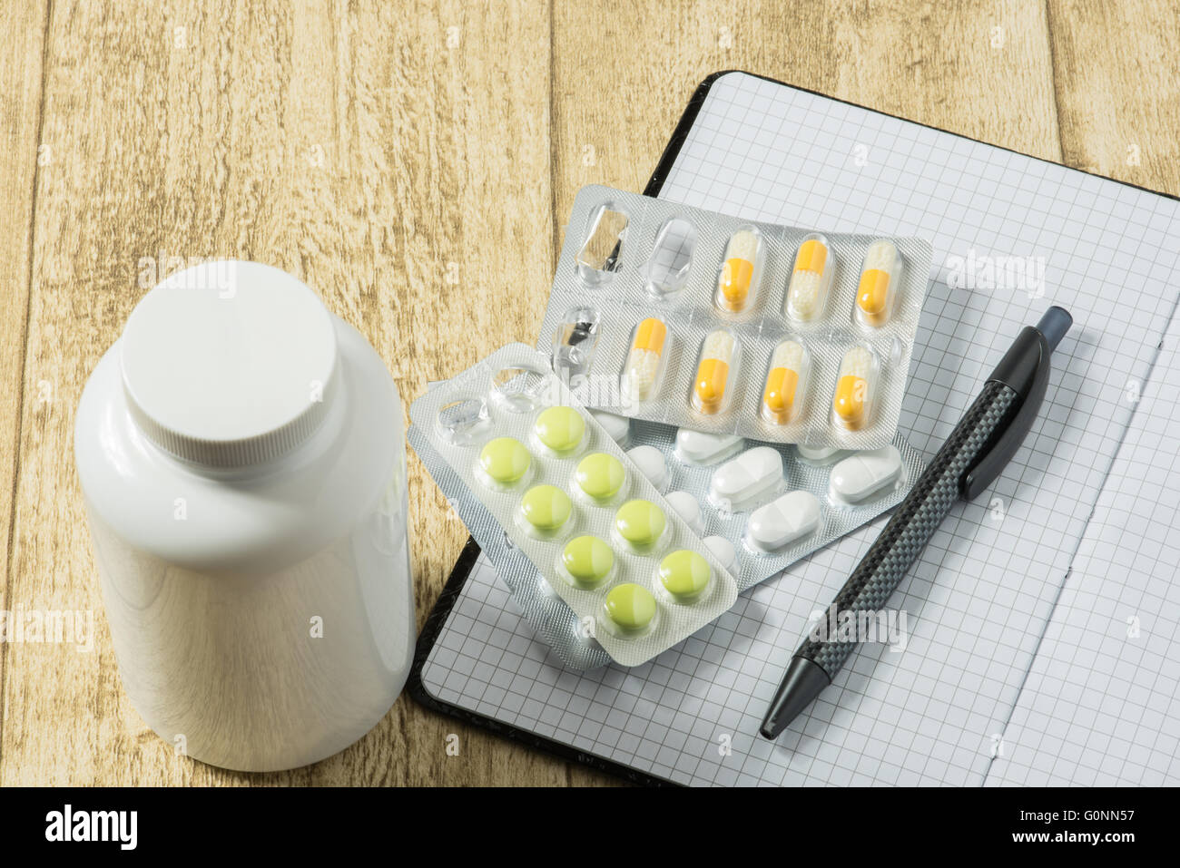 Compresse sulla scrivania in legno con notebook e penna Foto Stock