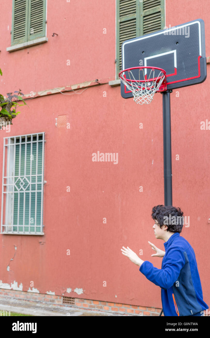 La formazione del ragazzo le posizioni difensive in una partita di basket grunge parco giochi vicino alla parete di pelatura di una vecchia casa Foto Stock