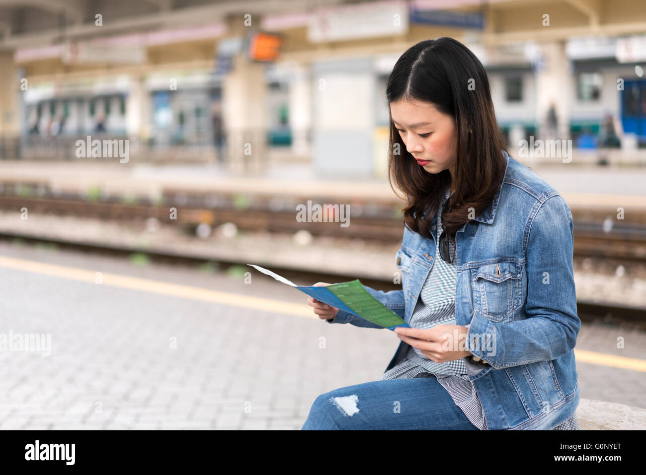 Bella donna asiatica studiare mappa alla stazione ferroviaria, con spazio di copia Foto Stock