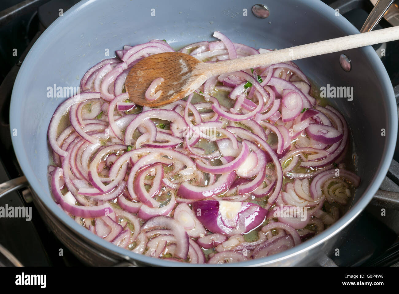 Sauteing cipolle rosse con olio nella padella di cottura sul fornello a gas  Foto stock - Alamy