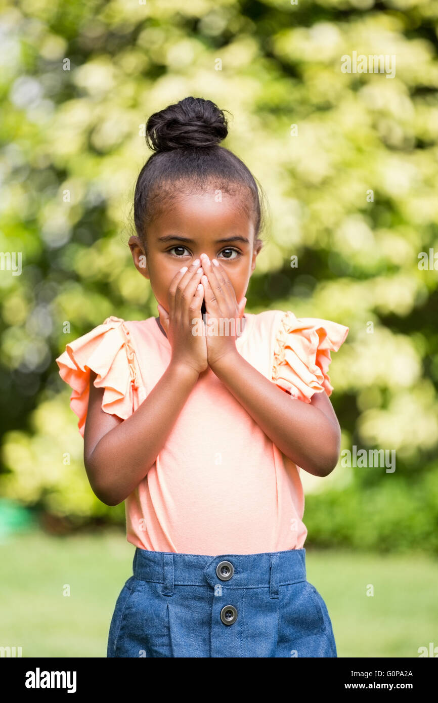 Bambina nascondendo la sua bocca in posizione di parcheggio Foto Stock