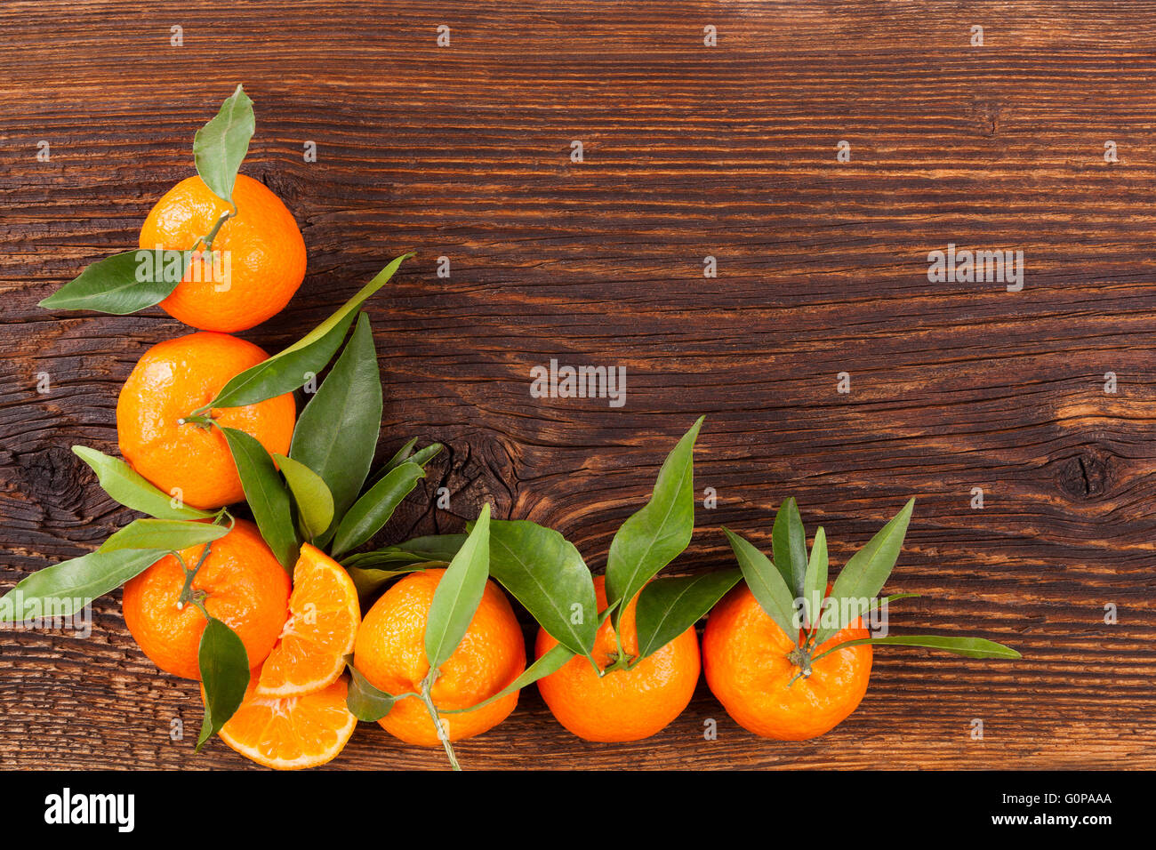Fresche e mature mandarini con foglie verdi e copia spazio su sfondo di legno. Organici di mandarini freschi, sani mangiando frutta. Foto Stock