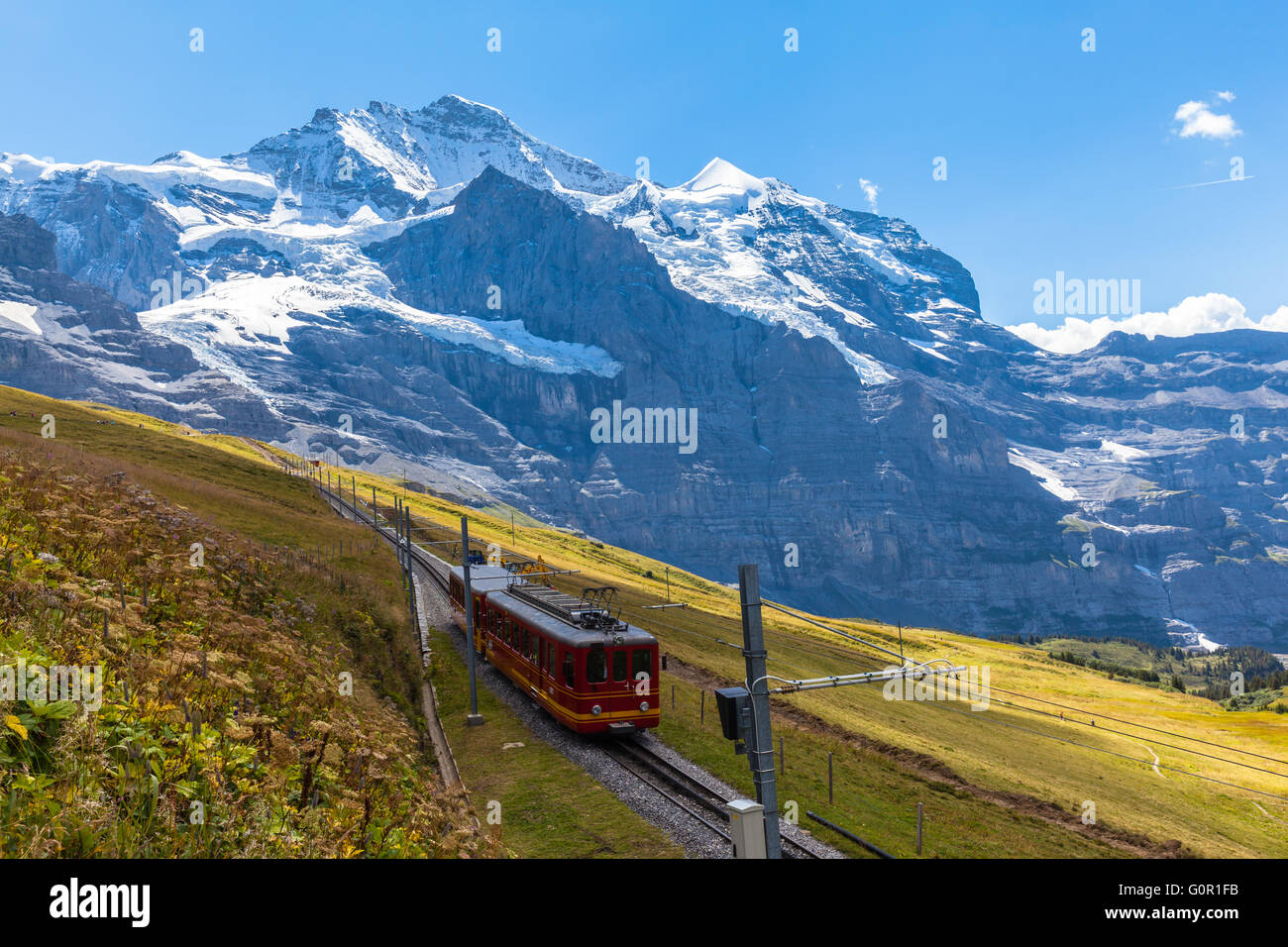 Treno di Jungfraubahn correndo verso Jungfraujoch sotto il famoso peak Jungfrau vicino alla stazione Eigergletscher su oberland OBE Foto Stock