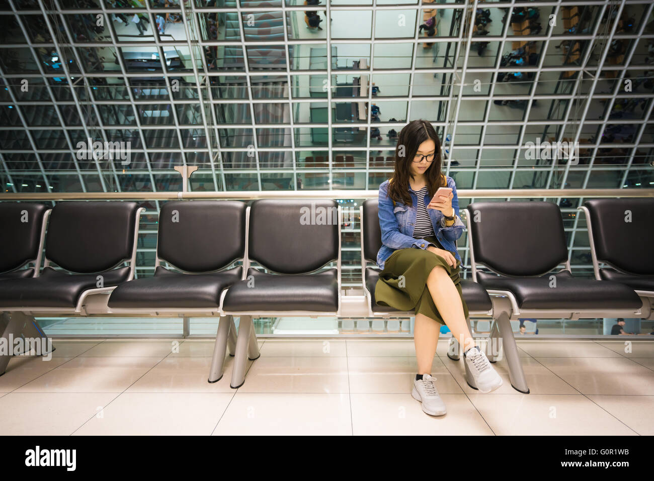 Bella ragazza asiatica utilizza lo smartphone, in attesa a salire a bordo del velivolo, concettuale Foto Stock