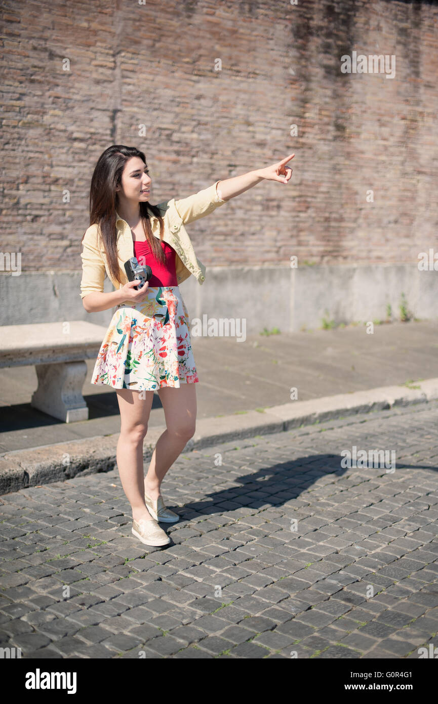 Giovane donna turista con fotocamera vintage sottolineando outdoor Foto Stock