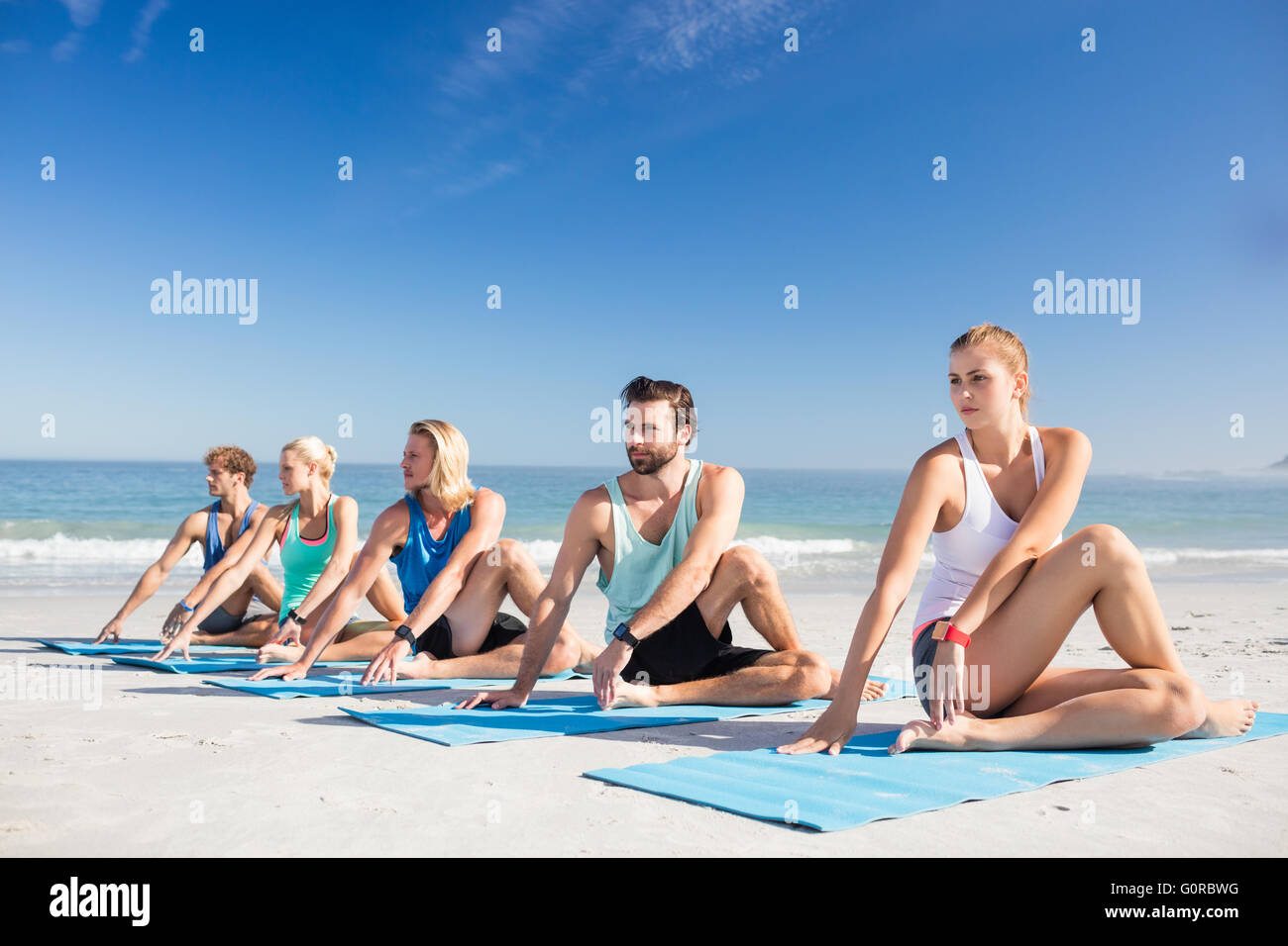 Persone che fanno lo yoga sulla spiaggia Foto Stock