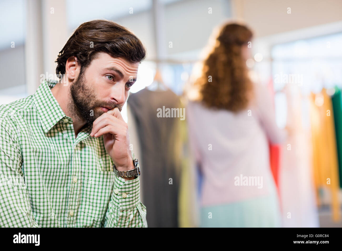 Annoiato uomo in attesa di sua moglie mentre la donna dal portabiti Foto Stock