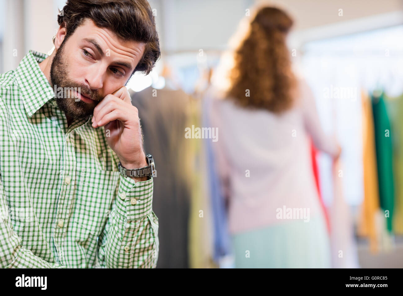 Annoiato uomo in attesa di sua moglie mentre la donna dal portabiti Foto Stock