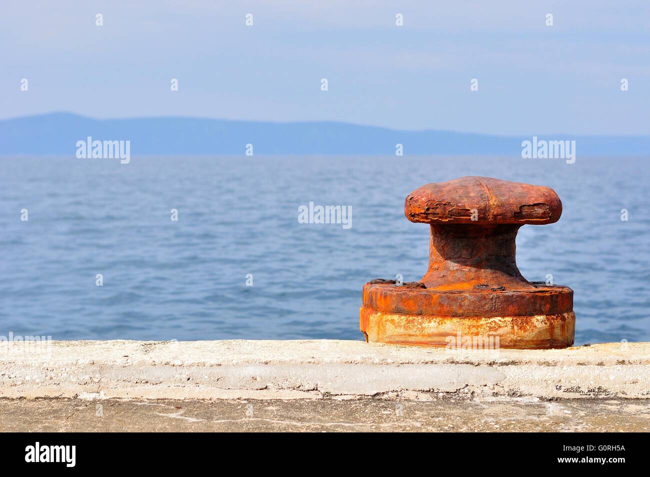 Vecchie e arrugginite bollard ormeggio sul porto di Podgora, Croazia. Spazio sul lato sinistro. Foto Stock