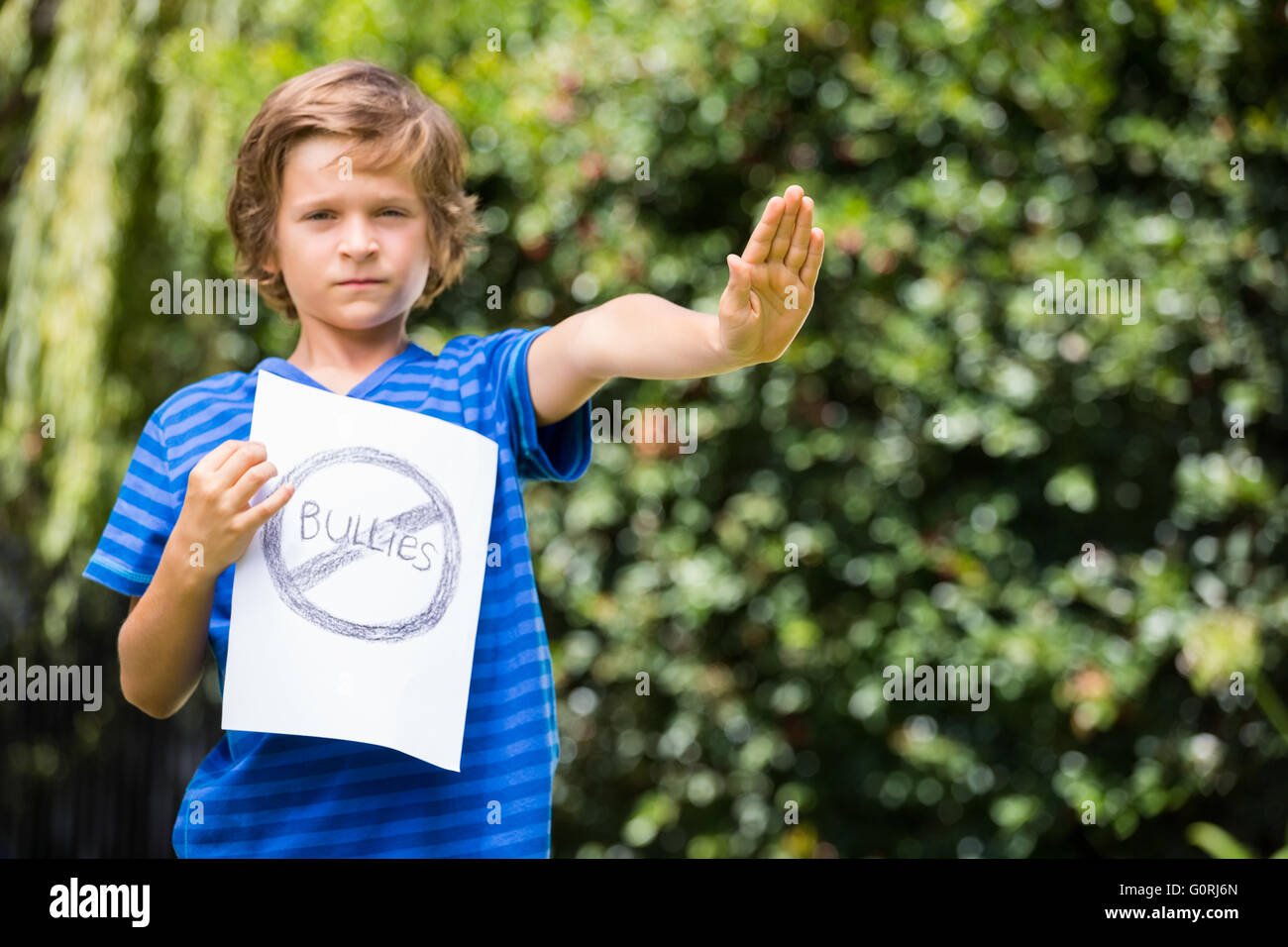 Ragazzo serio dire stop con la sua mano e tenendo premuto un messaggio Foto Stock