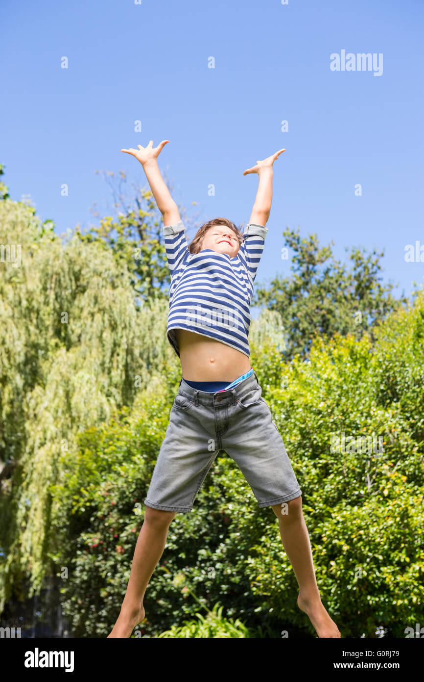 Carino boy jumping con bracci sollevati Foto Stock