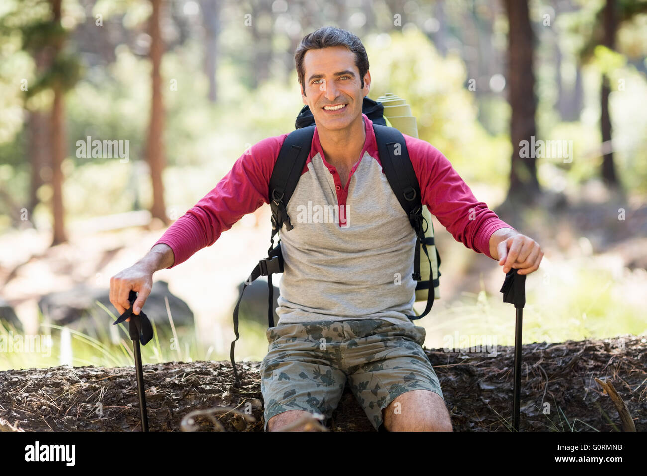 L'uomo escursionista sorridente e seduta su un albero Foto Stock
