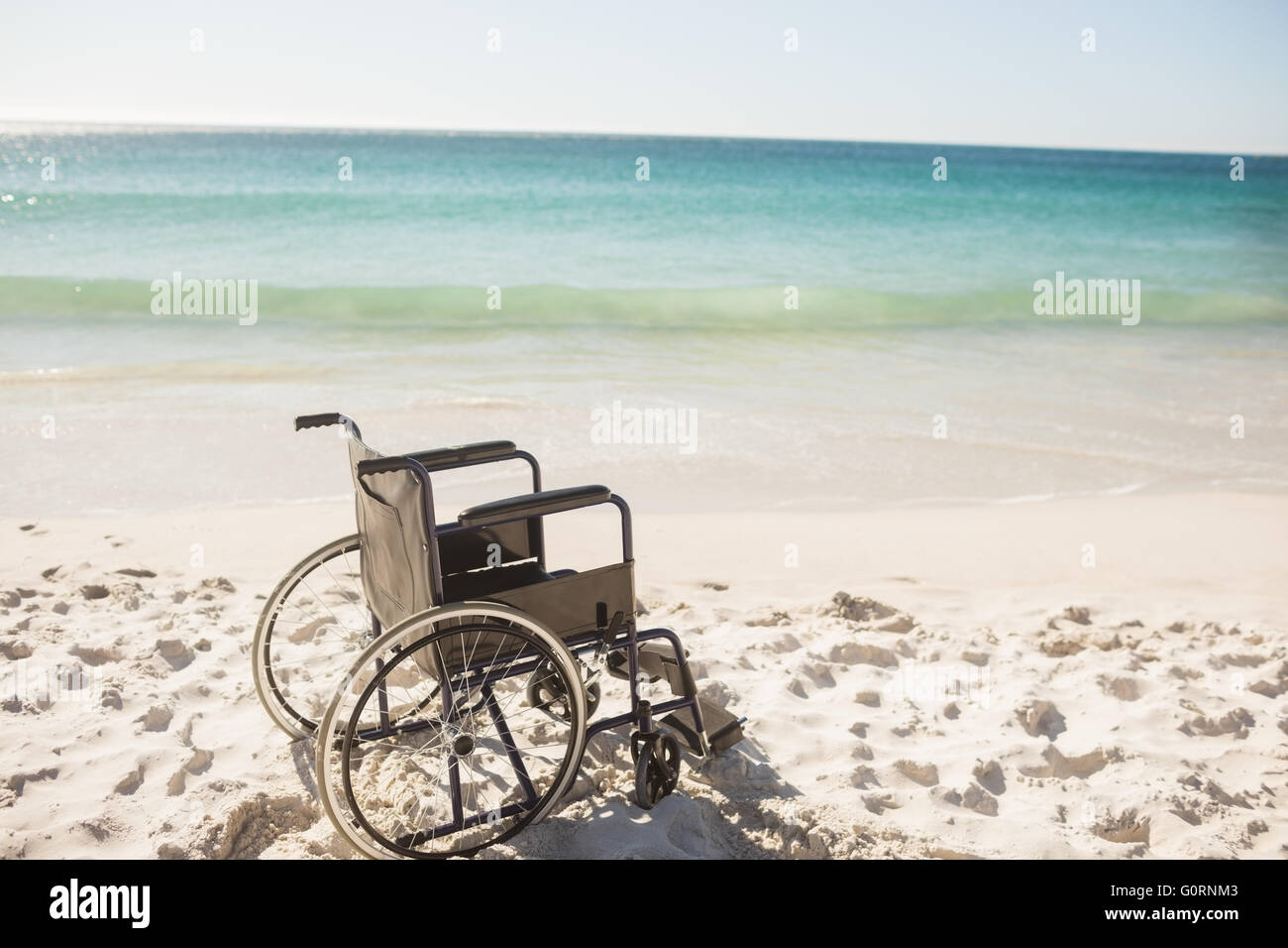 Sedia a rotelle nero sulla spiaggia Foto Stock